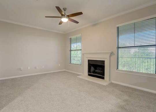 the living room has a fireplace and a ceiling fan at The Vista on Brodie, Austin, TX