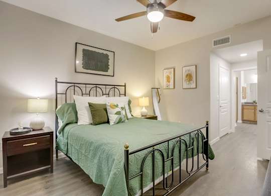 A bedroom with a bed, nightstand, and a ceiling fan.