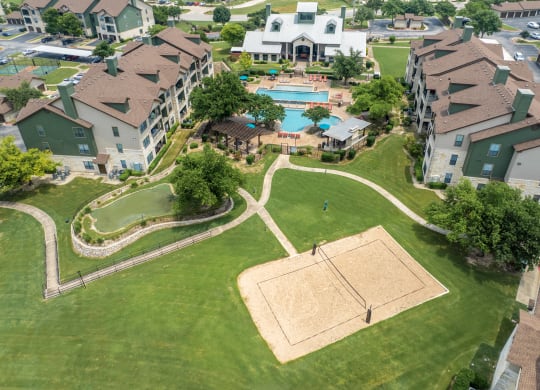 an aerial view of an apartment complex with a swimming pool and lawn