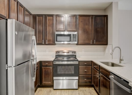 a kitchen with stainless steel appliances and wooden cabinets at Las Brisas Apartment Homes, Round Rock