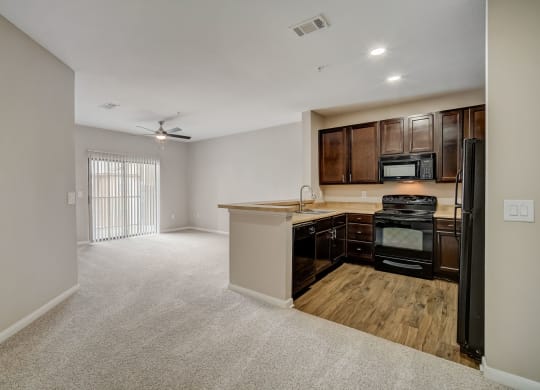 an empty living room with a kitchen with a stove and refrigerator at Las Brisas Apartment Homes, Texas, 78665