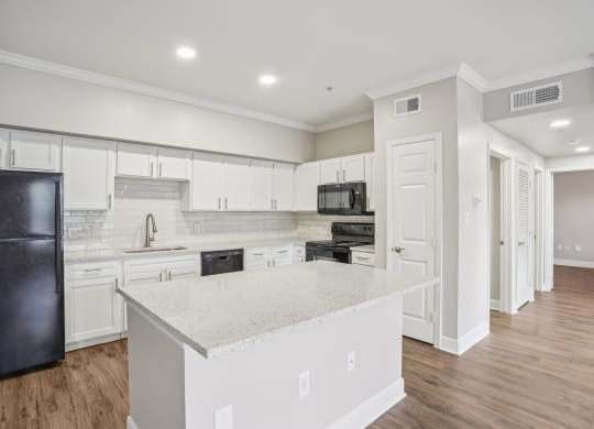 an open kitchen with white cabinets and a marble counter top at The Verandah, Austin, TX