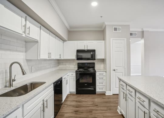 a white kitchen with white cabinets and a black stove and oven  at The Verandah, Austin, 78726
