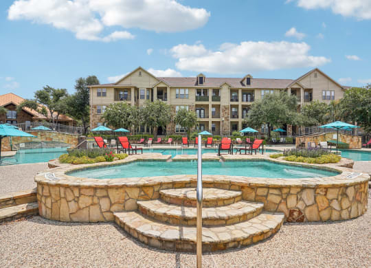 a swimming pool with a fountain and a hotel in the background at The Verandah, Austin, TX, 78726