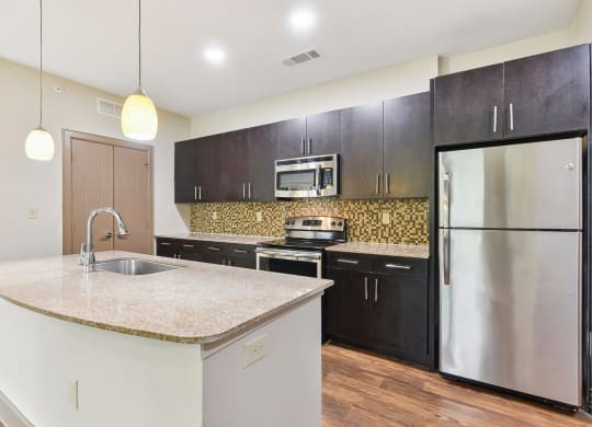 a kitchen with stainless steel appliances and a marble counter top at Lakeline East Apartments, Texas