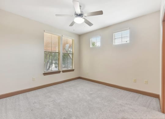 an empty room with a ceiling fan and two windows at Lakeline East Apartments, Texas, 78613