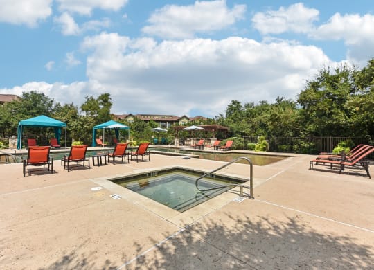the reserve at the falls pool and hot tub with chairs and umbrellas at Lakeline East Apartments, Cedar Park
