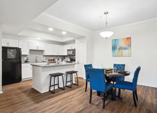 a living room with a table and chairs and a kitchen with a sink at La Ventura Apartments, Texas, 75093
