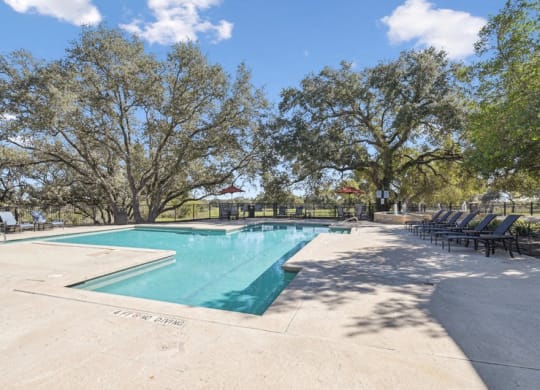 a swimming pool with chairs around it and trees