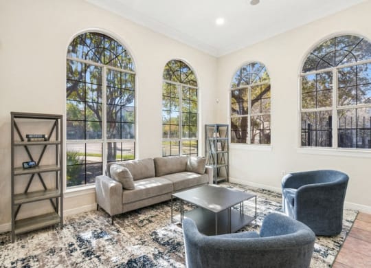 a living room with couches and chairs and windows