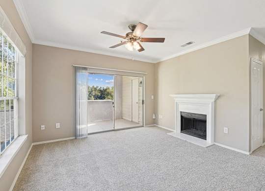 an empty living room with a fireplace and a ceiling fan