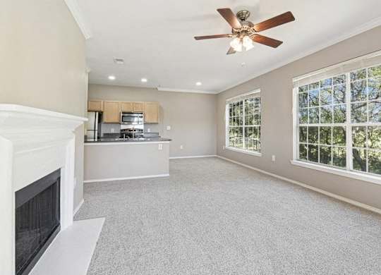 an empty living room with a fireplace and a ceiling fan
