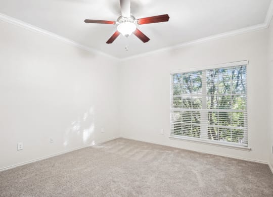 an empty living room with a ceiling fan and a window at La Ventura Apartments, Plano, 75093