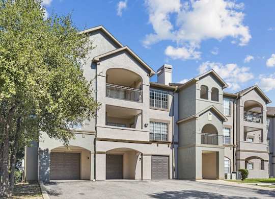 an apartment building with two garages and a tree