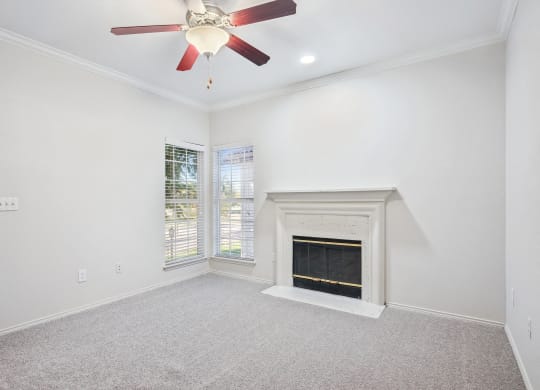 an empty living room with a fireplace and a ceiling fan at La Ventura Apartments, Plano, TX, 75093
