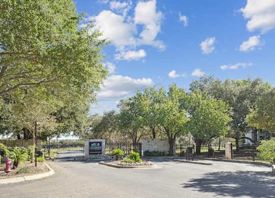 the entrance to a park with trees and a street