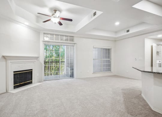 an empty living room with a fireplace and a ceiling fan at La Ventura Apartments, Plano, 75093