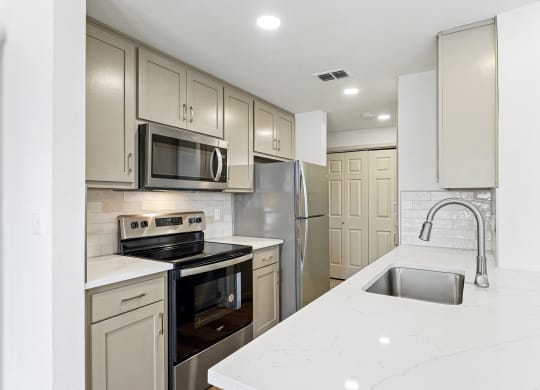 a white kitchen with stainless steel appliances and white counter tops at The Legends at Eagle Mountain Lake, Fort Worth, Texas