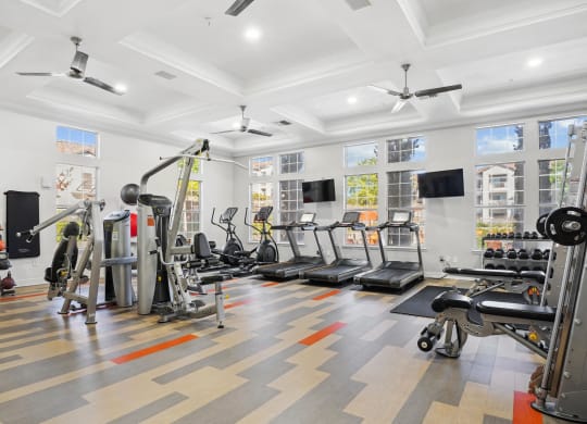 the gym has plenty of exercise equipment and windows at La Ventura Apartments, Texas, 75093