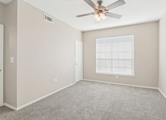 an empty room with a ceiling fan and a window