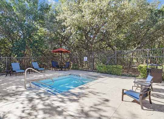 a pool with chairs and an umbrella in a backyard with trees