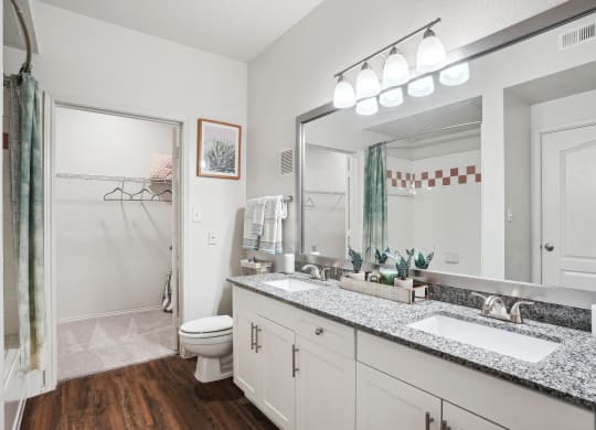 a bathroom with a large mirror and a sink and a toilet at La Ventura Apartments, Plano, Texas