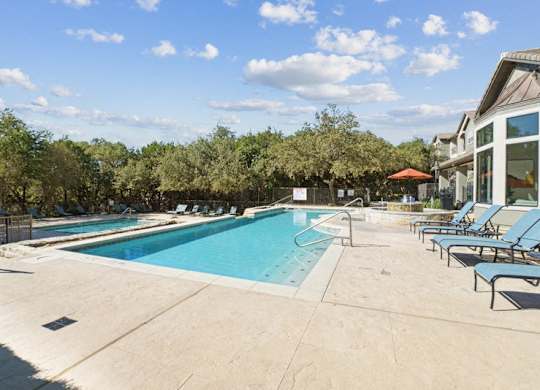 a swimming pool in a resort with chairs and a blue sky stock images