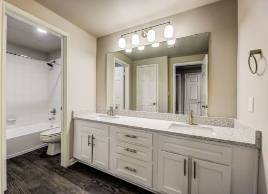 a bathroom with white cabinets and a mirror and a toilet at Ventana Oaks Apartments, Austin