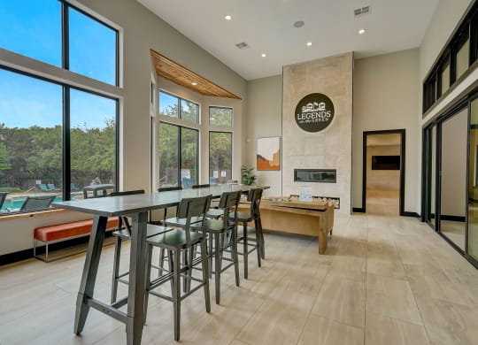 a long bar with stools in a kitchen with large windows