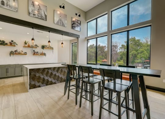 a bar with stools in a kitchen with large windows
