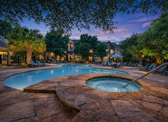 A large outdoor pool surrounded by trees and lounge chairs.