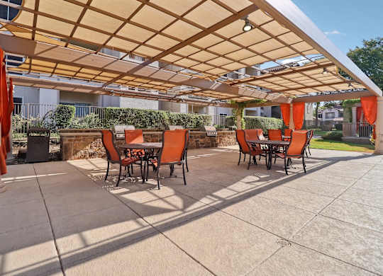 A patio with orange chairs and a wooden pergola.