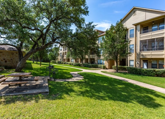 a picnic area with a table and benches in front of an apartment building at The Verandah, Austin, TX, 78726