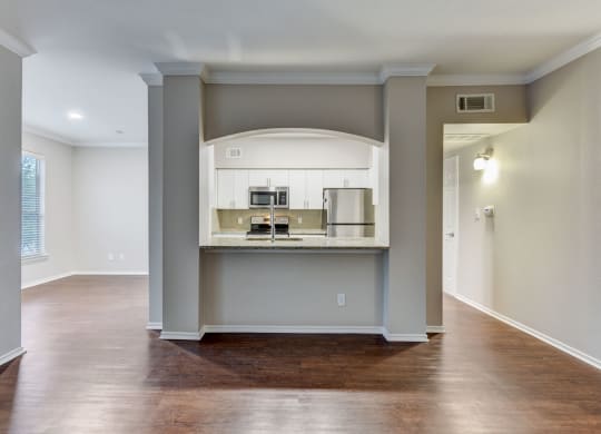 an empty living room and kitchen with a hard wood floor