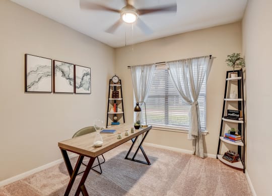 an office with a large window and a desk with a ceiling fan at Artisan Apartments & Shops, Austin, TX, 78729