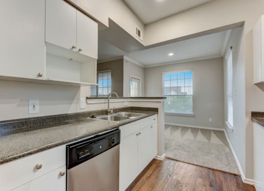 an empty kitchen with white cabinets and granite counter tops