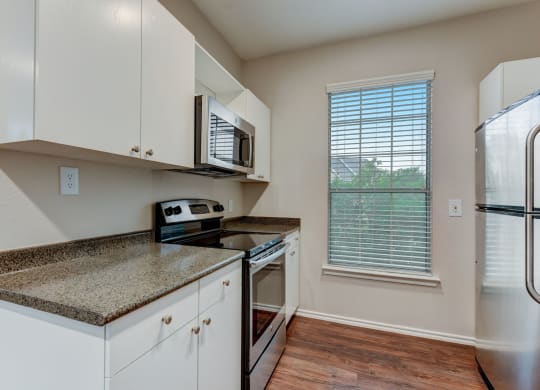 a kitchen with white cabinets and granite counter tops and a stainless steel refrigerator