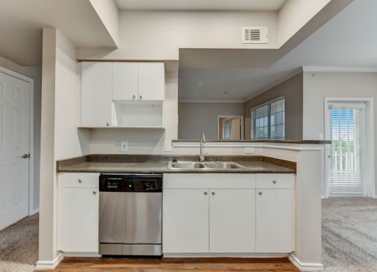 an empty kitchen with white cabinets and a stainless steel dishwasher
