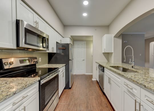 a kitchen with granite counter tops and white cabinets at Stone Oak @ Parmer, Austin, TX