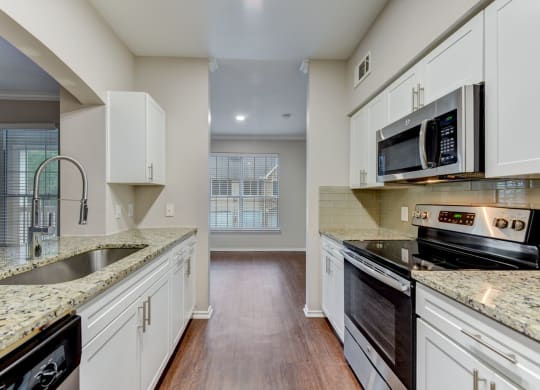an empty kitchen with white cabinets and granite counter tops at Stone Oak @ Parmer, Austin, Texas