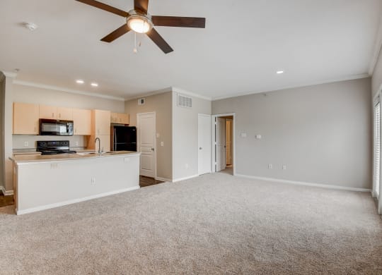 an empty living room with a ceiling fan and a kitchen at Artisan Apartments & Shops, Austin, Texas