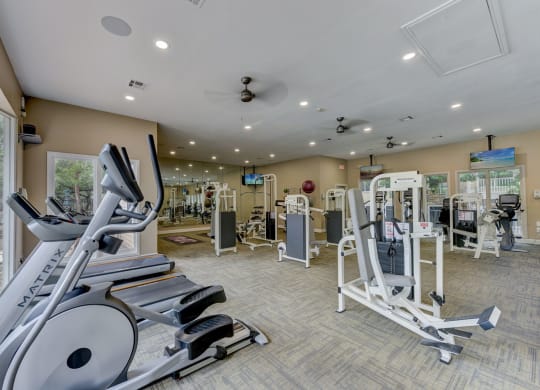 a gym with cardio equipment and weights in a building with windows
