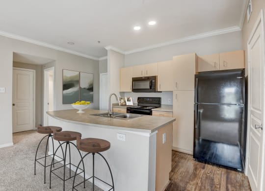 a kitchen with a large island with three stools at Artisan Apartments & Shops, Austin, TX