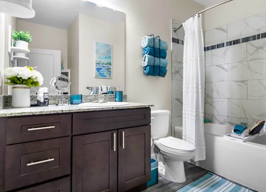 A bathroom with a white tub, a white toilet, a white sink, and a white shower curtain.
