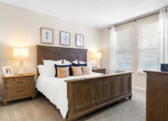 A bedroom with a large bed, a nightstand, and a wooden dresser.