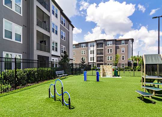 A playground with a green lawn, a slide, and a bench.