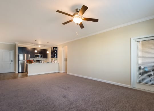 a living room with a ceiling fan and a kitchen in the background  at The Oasis at Manatee River, Bradenton, FL, 34211