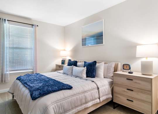 A bedroom with a bed, nightstand, and a painting on the wall.