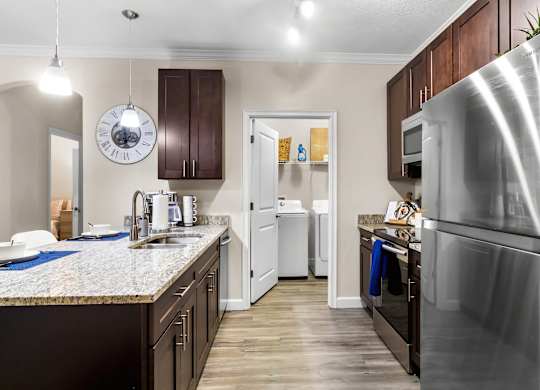 A kitchen with a refrigerator on the right and a sink with a faucet.