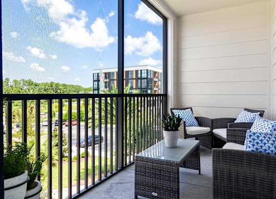 A balcony with a table and chairs overlooking a parking lot.